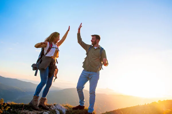 Par på toppen av ett berg skakar upp händerna — Stockfoto