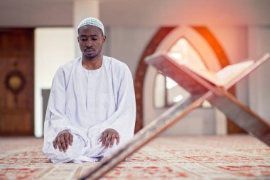 Dindar siyah Müslüman adam camide dua ediyor.