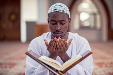 Dindar siyah Müslüman adam camide dua ediyor.