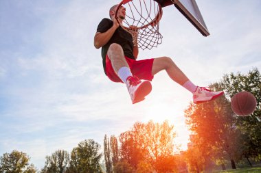 Genç adam zıplayıp smaç basıyor. Sokak basketbolu, basketbol oynuyor. Şehir otantik.