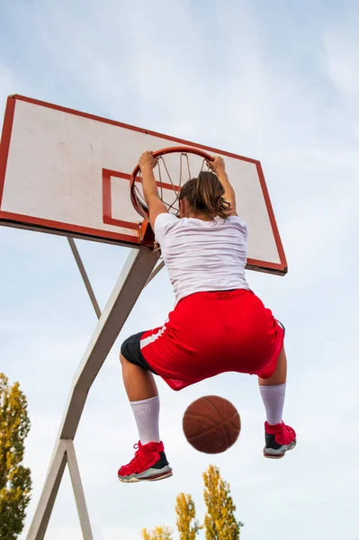 Τα θηλυκά παίζουν μπάσκετ στο γήπεδο. Γυναίκα παίκτης streetball κάνει slam dunk σε ένα παιχνίδι μπάσκετ. — Φωτογραφία Αρχείου