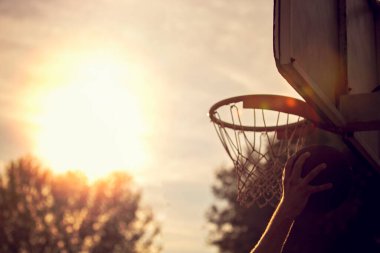 Genç adam zıplayıp smaç basıyor. Sokak basketbolu, basketbol oynuyor. Şehir otantik.