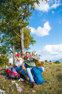 Neşeli genç çift dağlarda seyahat ederken dışarıda selfie çekiyorlar.