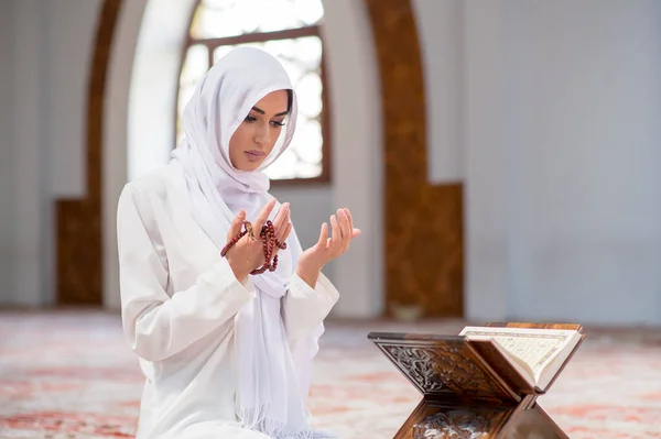 Jeune femme musulmane lisant le Coran dans la mosquée et la lumière du soleil tombant de la fenêtre — Photo