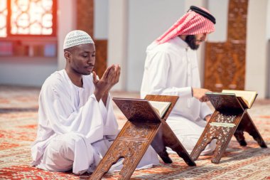 Dindar siyah Müslüman adam camide dua ediyor.