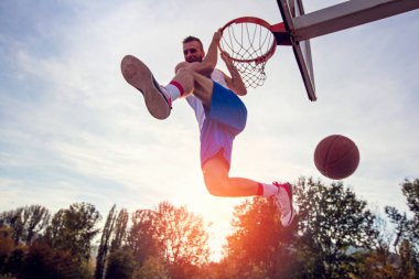Genç adam zıplayıp smaç basıyor. Sokak basketbolu, basketbol oynuyor. Şehir otantik.