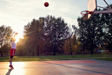 Kadın basketbolcu, sokaktaki basketbol sahasında ağaç dikme ve egzersiz yapıyor.
