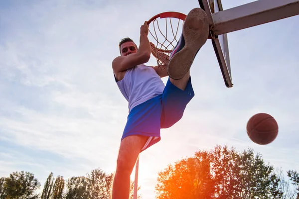 Joven saltando y haciendo un fantástico slam dunk jugando streetball, baloncesto. Auténtico urbano. — Foto de Stock