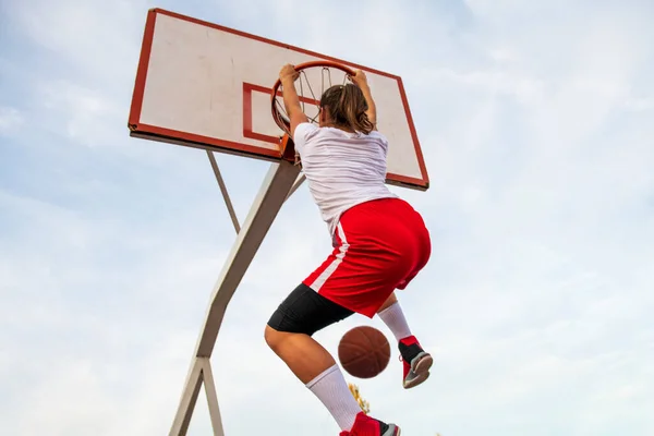 Samice hrají basketbal na pouličním hřišti. Žena streetball hráč dělat slam ponořit do basketbalové hry. — Stock fotografie