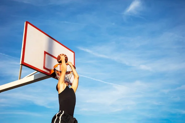 Jovem pulando e fazendo um fantástico slam dunk jogando streetball, basquete. Urbano autêntico. — Fotografia de Stock