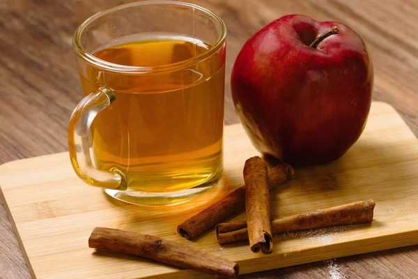 Cam fincan çay tarçın ve ahşap tahta üzerinde bir elma ile