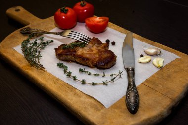 Baharatlar ve sebzeler ile ahşap bir eski kesme tahtası üzerinde sulu biftek biftek. Siyah bir arka plan üzerinde restoran menüleri için metin tasarım için. Gıda arka plan.