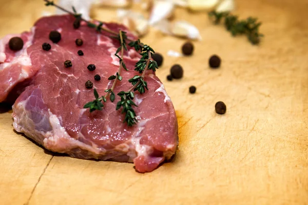 Bir kesme tahtası üzerinde ham mermer sığır eti. Siyah bir arka plan üzerinde