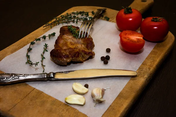 Baharatlar ve sebzeler ile ahşap bir eski kesme tahtası üzerinde sulu biftek biftek. Siyah bir arka plan üzerinde restoran menüleri için metin tasarım için. Gıda arka plan.