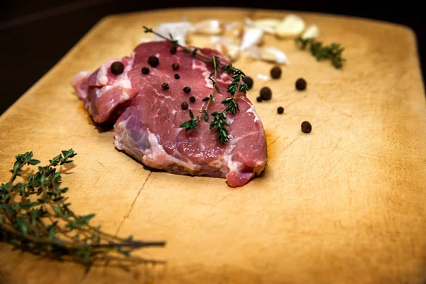 Bir kesme tahtası üzerinde ham mermer sığır eti. Siyah bir arka plan üzerinde