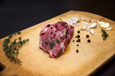 Bir kesme tahtası üzerinde ham mermer sığır eti. Siyah bir arka plan üzerinde