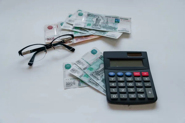Para Rusya'da. Banknot beş ve bir bin ruble, arka plan, tablo, gözlük ve bir hesap makinesi seçici odak.