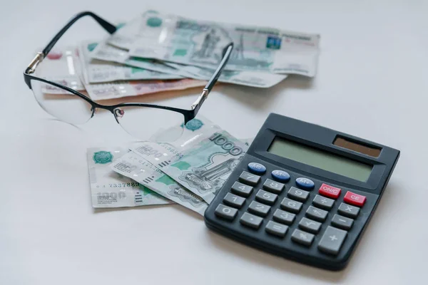 Para Rusya'da. Banknot beş ve bir bin ruble, arka plan, tablo, gözlük ve bir hesap makinesi seçici odak.