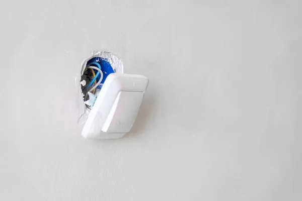 Beyaz bir duvarda kırık bir elektrik düğmesi. — Stok fotoğraf