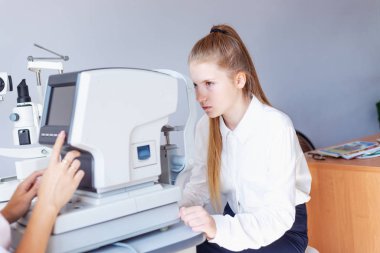 Bir optometrist ya da optometrist retina, göz lensi ve göz içi basıncı özel göz doktoru ekipmanları üzerinde teşhis eder. Beyaz bluzlu kız öğrenci.