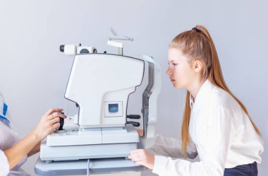 Bir optometrist ya da optometrist retina, göz lensi ve göz içi basıncı özel göz doktoru ekipmanları üzerinde teşhis eder. Beyaz bluzlu kız öğrenci.