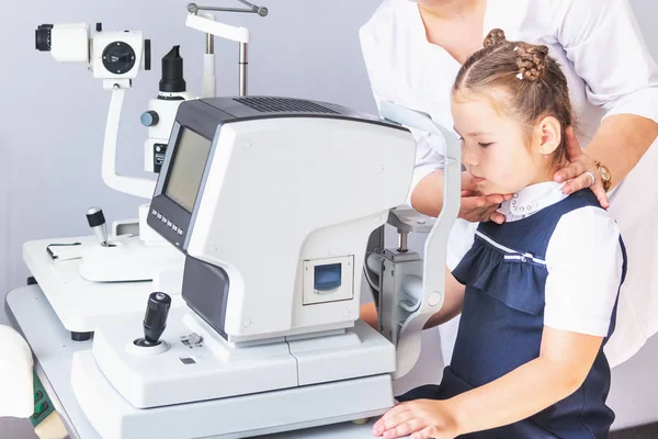 Bir optometrist ya da optometrist retina, göz lensi ve göz içi basıncı özel göz doktoru ekipmanları üzerinde teşhis eder. Beyaz bluzlu kız öğrenci.