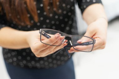 Güzel, modern bir kadın optik mağazasından yeni okuma gözlüğü seçiyor. Vizyon düzeltmesi. Oftalmoloji. Kapatmak için