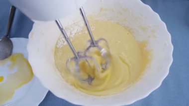 Hamur yapan bir kızın yavaş çekim üst görüntüsü. Mangırı elektrikli mikserle karıştırıyorum. Evde yemek pişirmek..