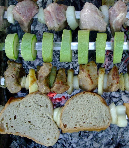 O shashlik grelhado cozinha-se no fogo. Carne grelhada e abobrinha — Fotografia de Stock