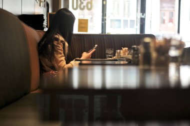 Anonim kadın Cafe telefon bakarak