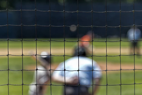 Suddig baseball spel sett genom nät — Stockfoto