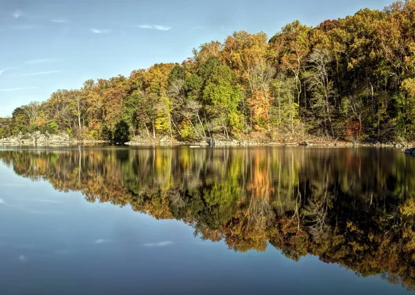 Renkli sonbahar yaprakları ve mavi gökyüzü suya yansıyan