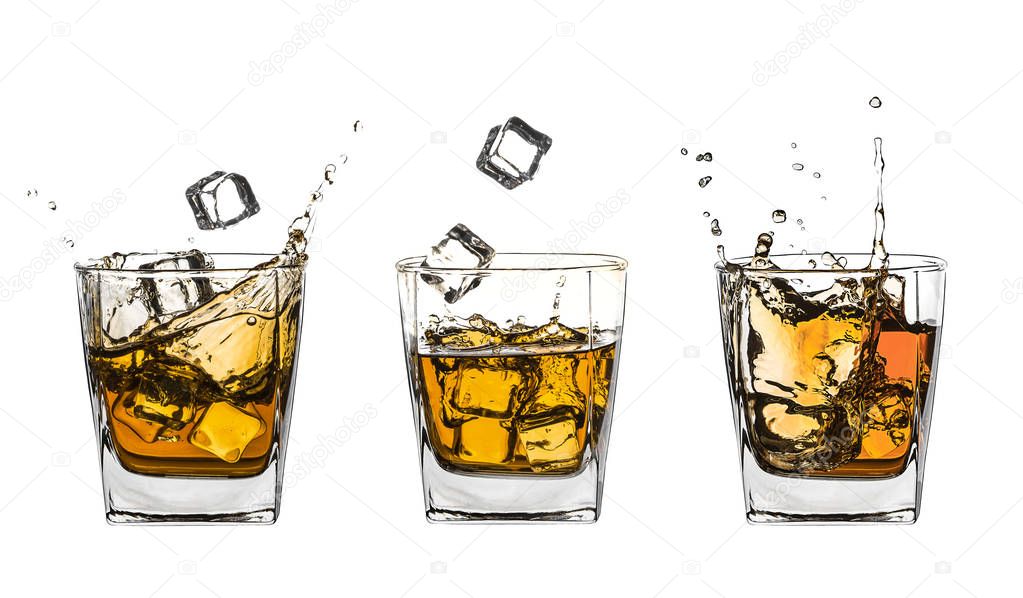 Three glasses of splashing whiskey with ice on white