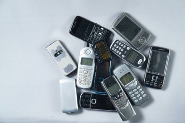 Birkaç eski cep telefonları beyaz zemin üzerinde bir yığın yalan