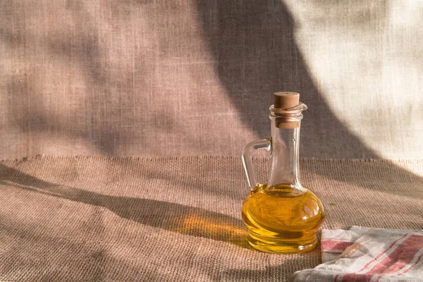 テキスト用の場所と古い黄麻布の背景にナプキンのガラス瓶の中のひまわり油 — ストック写真