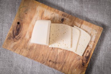 bir eski kesme tahtası üzerinde sıradan sarı peyniri dilimlenmiş