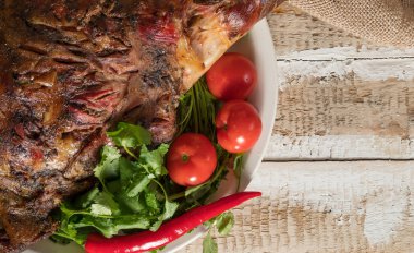 taze domates yeşil ve acı biber eski bir ahşap yüzeyde bir tepside bütün yalanlarla pişmiş kuzu eti bacak kavrulmuş