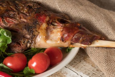 taze domates yeşil ve acı biber eski bir ahşap yüzeyde bir tepside bütün yalanlarla pişmiş kuzu eti bacak kavrulmuş