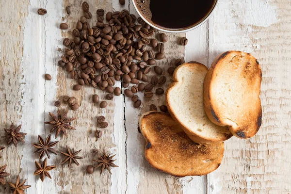 coffee Cup, coffee beans of toast scattered on the rough wooden surface background