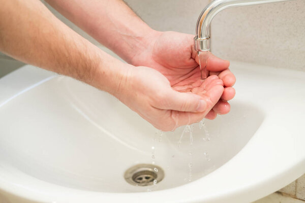 men's hand clean water is poured from the faucet over the sink