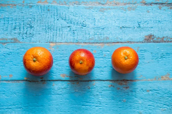 Tre Röda Apelsiner Ligga Blå Trä Yta Bakgrund — Stockfoto