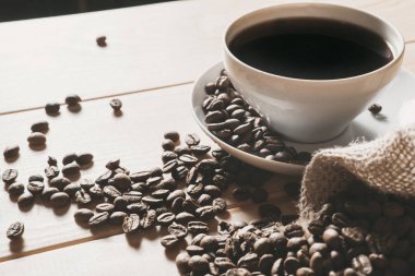 kahve kavrulmuş kahve çekirdekleri bir ahşap yüzeye dağınık ile beyaz bir bardağa dökülür