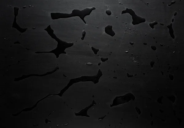 wet traces of water on a black matte surface texture background