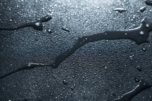 wet traces of water on a black matte surface texture background