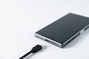 siyah cep telefonu dahil hafif bir arka plan üzerinde şarj tel