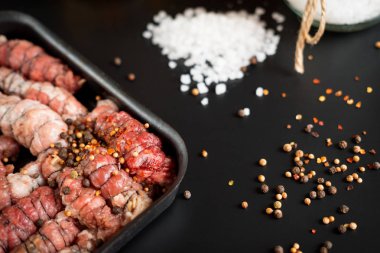 yalan bir kızartma tavası ayakta serpilir baharat ve büyük tuz siyah bir zemin üzerine kıyılmış et sarılı rulo