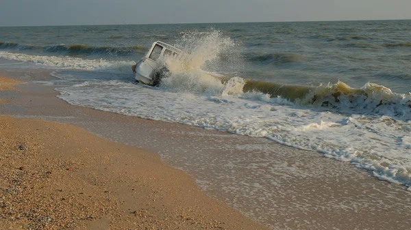 a sunken plastic yacht with a outboard motor beats the waves of the sea on a sandy beach