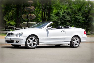 Rostov-on-Don, Rusya, 06: 09, 2013. Beyaz araba bir yaz günü yeşil ağaçların yanında..