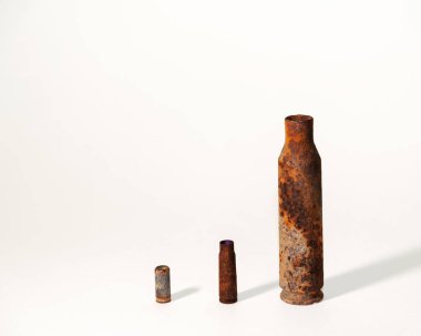 Beyaz bir arka planda ateşli silahtan çıkan eski paslı mermiler.