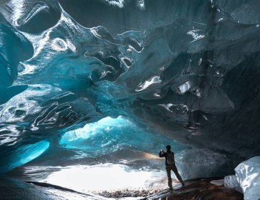 man stands inside the glacier cave of the Alibek mountain glacier in Dombay